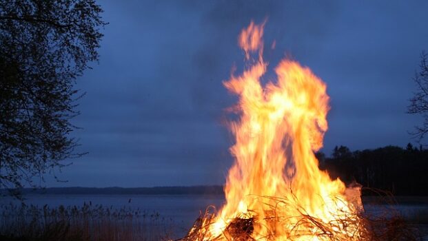 Suomalainen kansanperinne juhannuskokko järven rannalla kesäyössä.