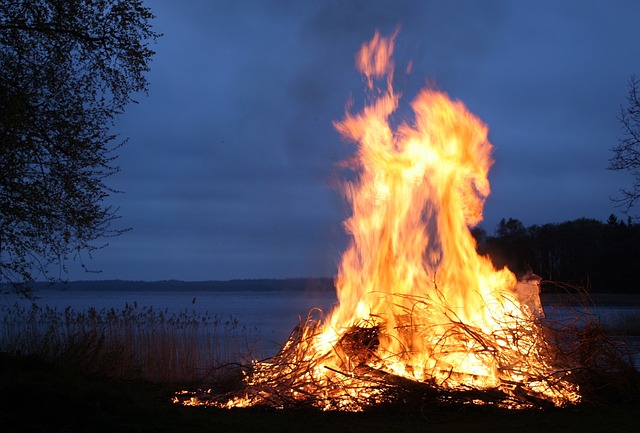 Suomalainen kansanperinne juhannuskokko järven rannalla kesäyössä.