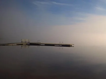 Aamusumussa tyynen järven rannalla oleva laituri.