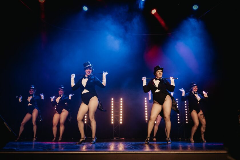 Kuvassa burleskiryhmä Vermillion Dames poseeraa lavalla silinterihatuissa