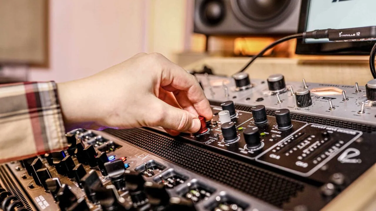 Kuvassa käsi säätämässä Rupert Neve Designs MBP Portico II laitteen nappulaa. Studiossa laadukasta outboard laitteistoa.