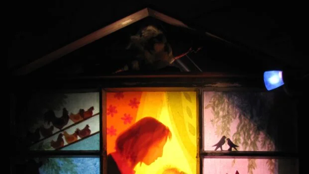Värikkäitä ikkunalaseja vierekkäin, joissa kuvataan erilaisia eläimiä: lintuja, hevonen, lehmä ja lampaita. Keskimmäisessä ikkunassa nainen ja nukkuva lapsi.
