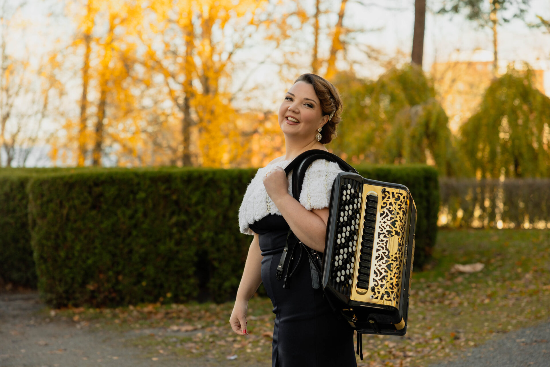 Henna Leppänen on syksyisessä säässä ulkona harmonikka selässään.