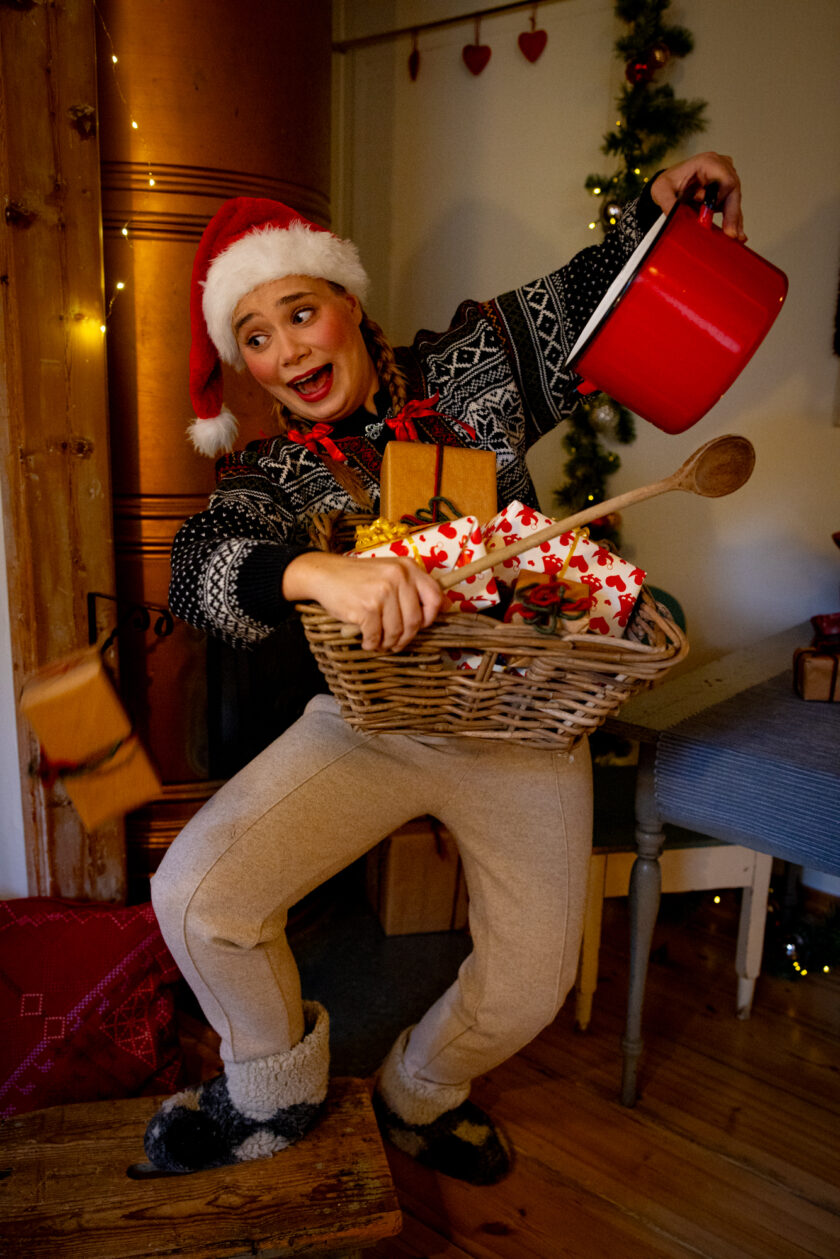 Höpsö joulutonttu tanssii. Toisessa, kohotetussa kädessä hänellä on punainen kattila ja toisessa kädessä hän pitelee täynnä koria, jossa on paketteja ja puukauha. Yksi paketti on tippumasa korista. Tunnelma on hulvaton.