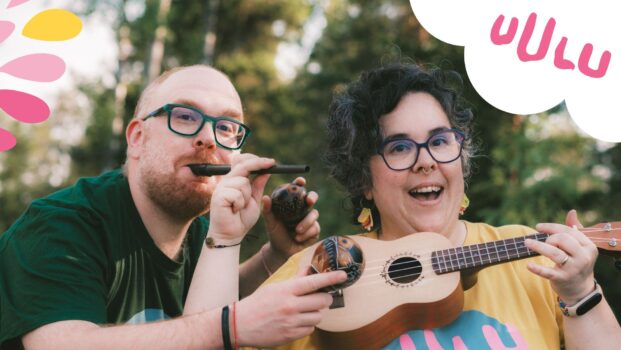 Kuvassa Palago-yhtyeen jäsenet Iago ja Paloma poseeraavat monien soittimien kanssa. Iago puhaltaa huiluun ja pitelee marakasseja, Palomalla on edessään ukulele-kitara. Taustalla näkyy puita ja hiukan valoisaa taivasta. Tunnelma on energinen ja innostunut. Kuvan vasemmassa yläkulmassa on värikkäitä pisarakuvioita ja oikeassa yläkulmassa Uulun vaaleanpunainen logo valkoisen pilvikuvion päällä.