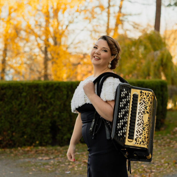 Henna Leppänen on syksyisessä säässä ulkona harmonikka selässään.