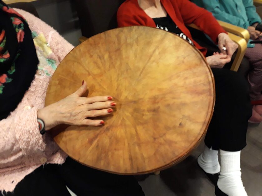 Lähikuva soittajan käsistä lyömässä rytmiä suurella kehärummulla musiikkiumppahetkellä.