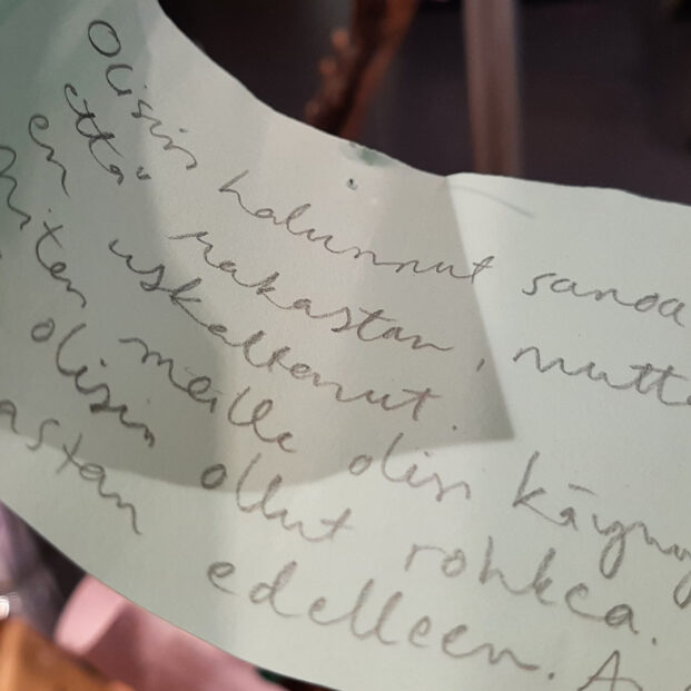 Kuvassa on vaalea paperinpala, johon on kirjoitettu kaunokirjoituksella: olisin halunnut sanoa, että rakastan, mutta en uskaltanut. Miten meille olisi käynyt, jos olisin ollut rohkea. Rakastan edelleen.