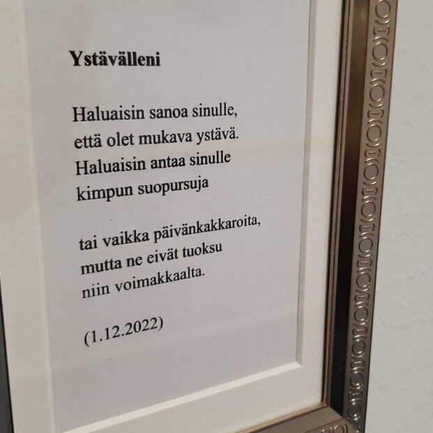 Kuvassa on lähikuva taulusta, jossa on teksti "Ystävälleni, Haluaisin sanoa sinulle, että olet mukava ystävä. Haluaisin antaa sinulle kimpun suopursuja tai vaikka päivänkakkaroita, mutta ne eivät tuoksu niin voimakkaalta. (1.12.2022).