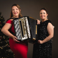 Henna Leppänen on kuvan vasemmassa reunassa harmonikka sylissä ja laulaja Johanna Debreczeni kuvan oikealla puolella. Kuvan tunnelma on jouluinen ja taustalla on joulukuusi.