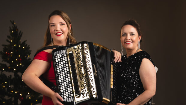 Henna Leppänen on kuvan vasemmassa reunassa harmonikka sylissä ja laulaja Johanna Debreczeni kuvan oikealla puolella. Kuvan tunnelma on jouluinen ja taustalla on joulukuusi.